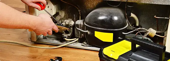 Refrigerator repair technician fixing the compressor and wiring in Sobieski, WI