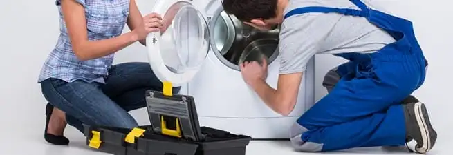 Washer repair technician inspecting a front-load washing machine with tools in Green Bay, WI