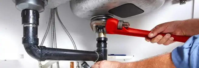Garbage disposal repair technician tightening the sink drain and disposal connection in Green Bay, WI