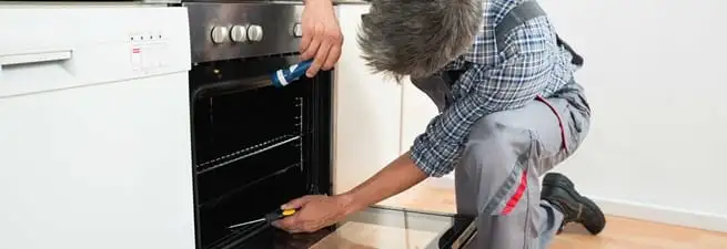 Oven repair technician inspecting and servicing an electric oven in Green Bay, WI
