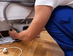 Appliance repair technician fixing refrigerator water line and connections in Green Bay, WI