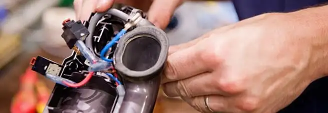 Vacuum repair technician reconnecting wiring and components in Green Bay, WI