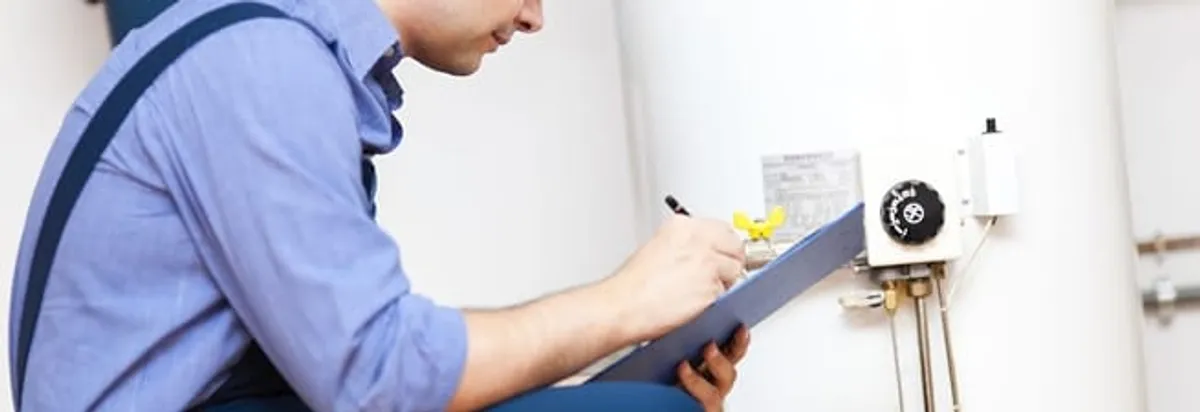 Water heater repair technician inspecting the unit and recording service notes in Green Bay, WI