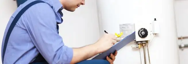 Water heater repair technician inspecting the unit and recording service notes in Green Bay, WI
